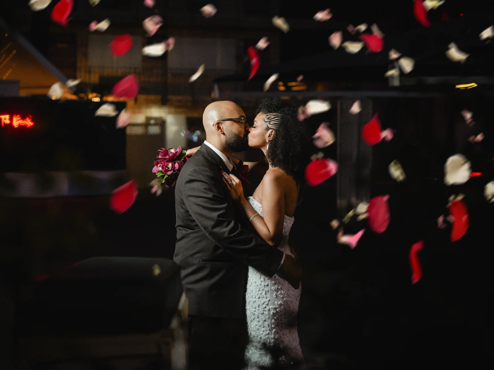 Couple kissing with rose petals falling around them at night at a Las Vegas wedding chapel
