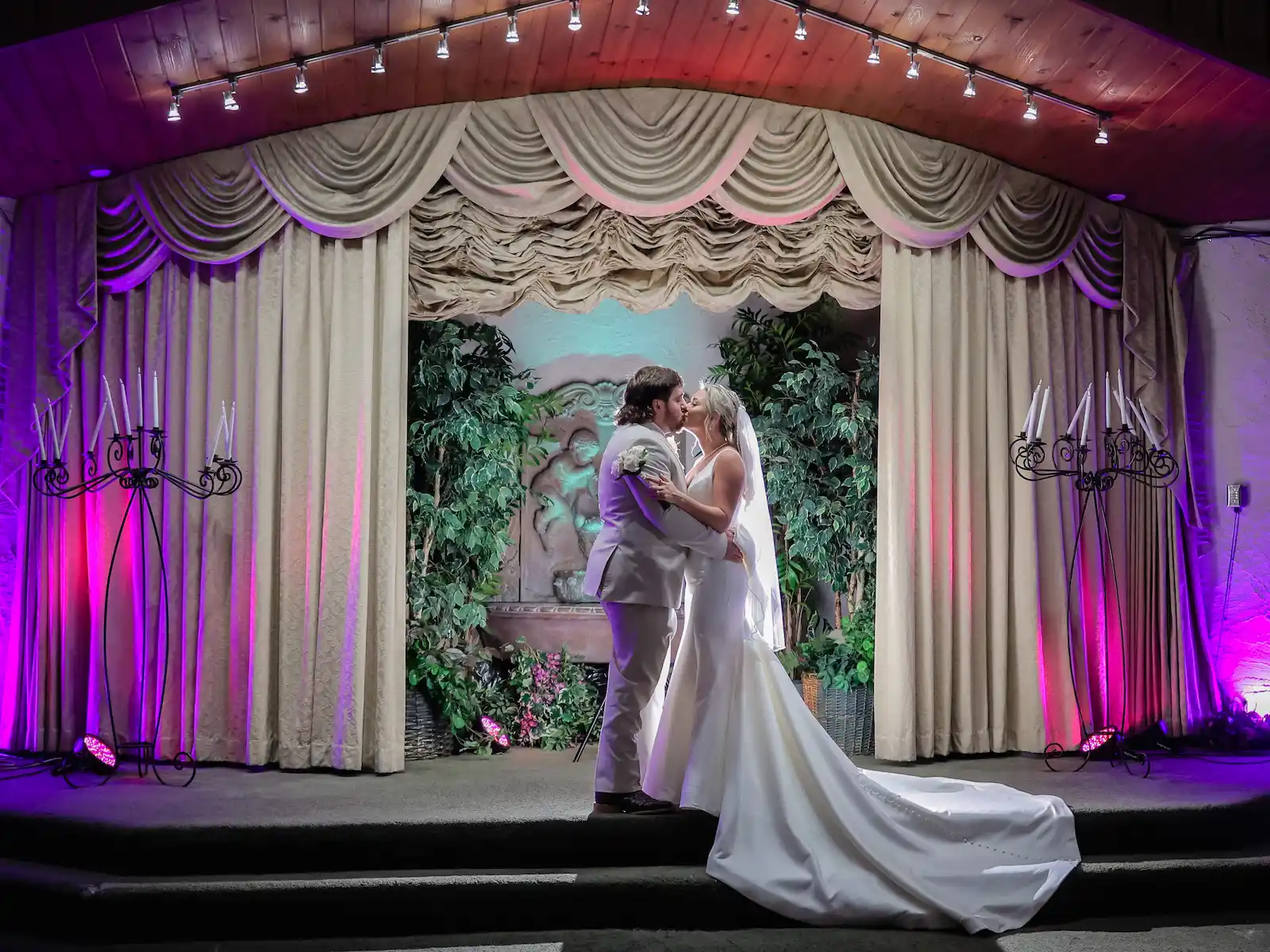 Bride and groom sharing their first kiss at the altar of a Las Vegas wedding chapel with purple lighting and candelabras