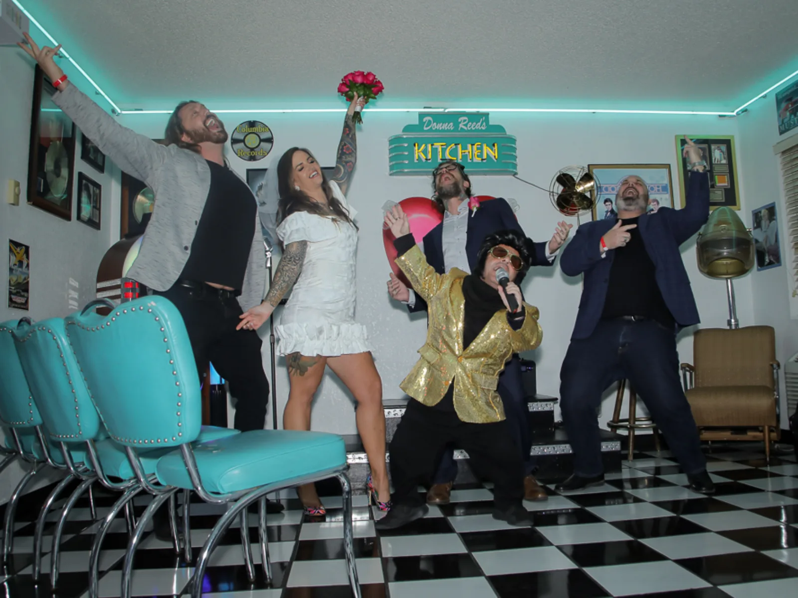 Elvis las vegas tribute singer entertaining lively wedding group inside neon diner.
