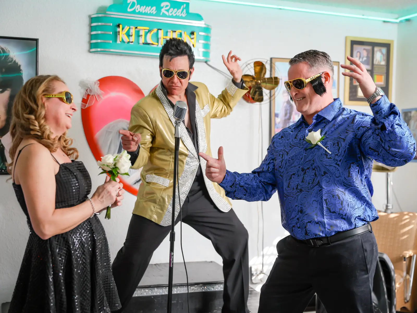 Elvis impersonator in gold jacket singing with wedding guests on diner stage