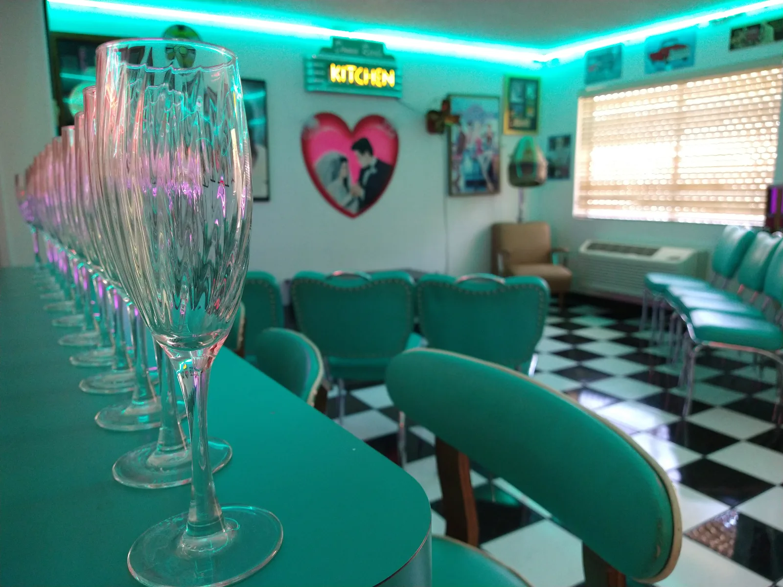 Row of sparkling champagne flutes arranged on mint green diner counter