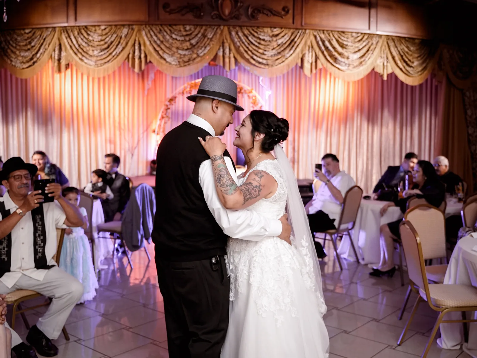 Bride and groom sharing first dance surrounded by seated wedding guests.