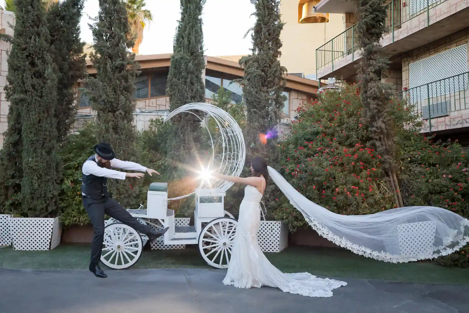 Bride and groom posing playfully with a white Cinderella carriage at a Las Vegas wedding venue