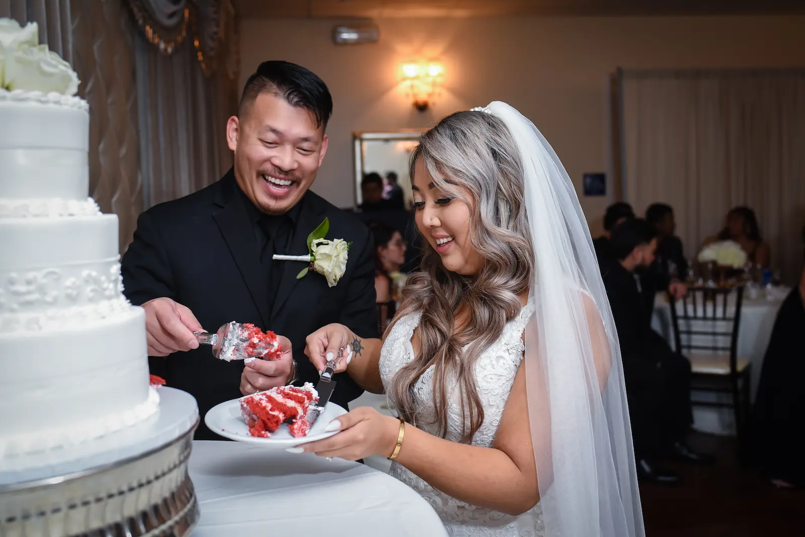 Bride and groom laughing while cutting red velvet wedding cake at a Las Vegas reception
