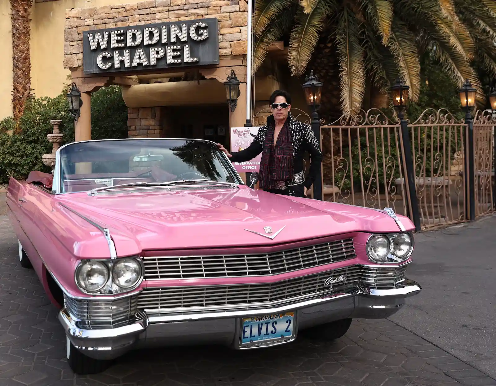 Elvis impersonator posing with pink Cadillac outside Viva Las Vegas Wedding Chapel