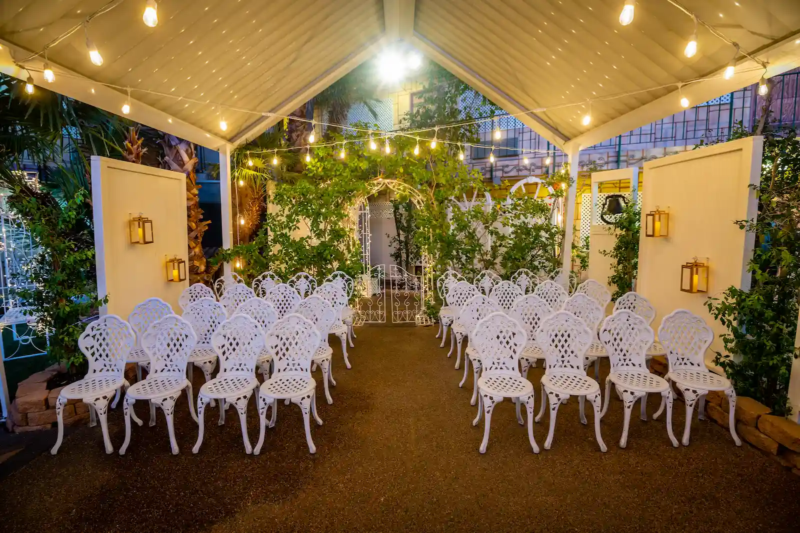 Bell Garden outdoor wedding venue at night with white iron chairs, string lights, and garden arbor at Viva Las Vegas