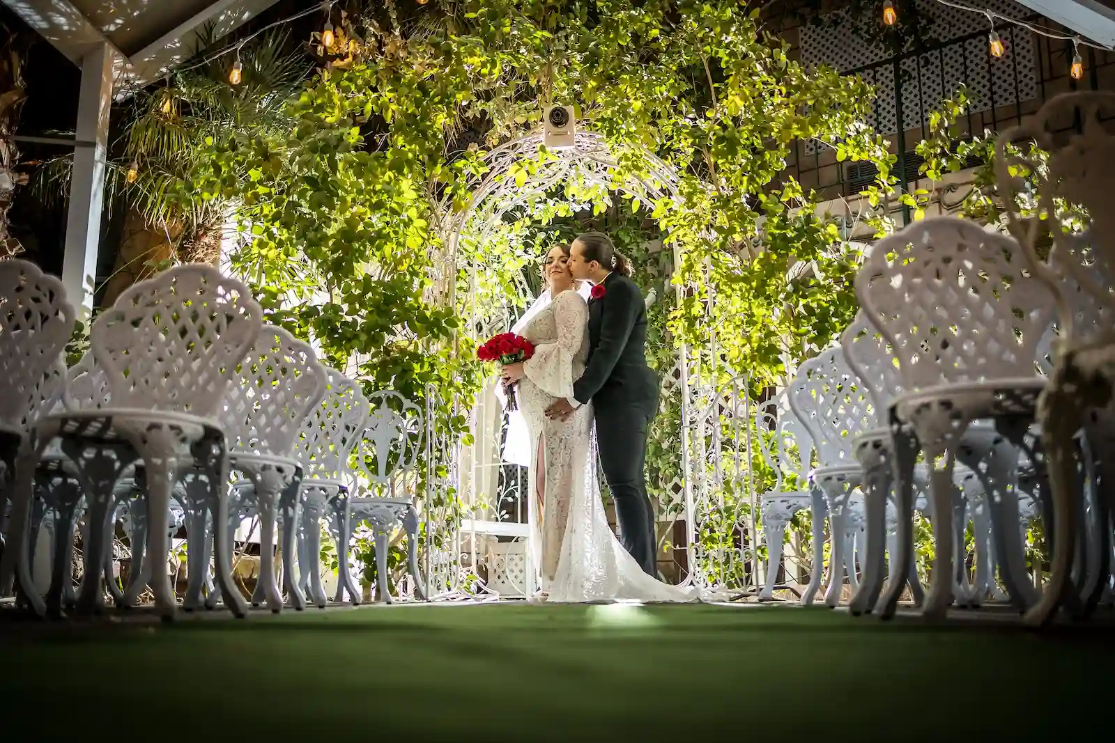 Couple sharing first kiss under a lush ivy arch at outdoor garden wedding chapel in Las Vegas