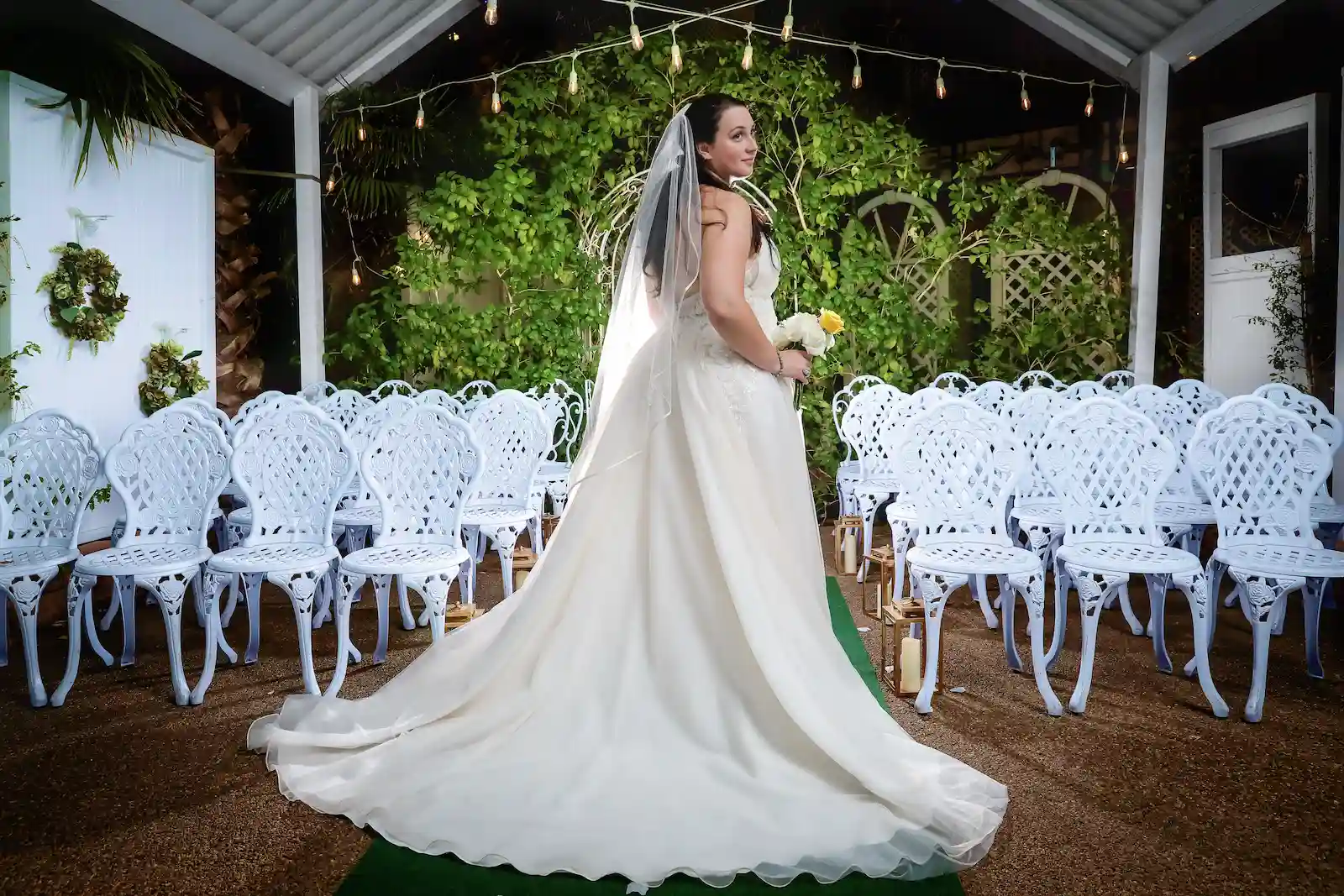 Bride in gown with cathedral train and veil posing in outdoor garden wedding chapel aisle in Las Vegas