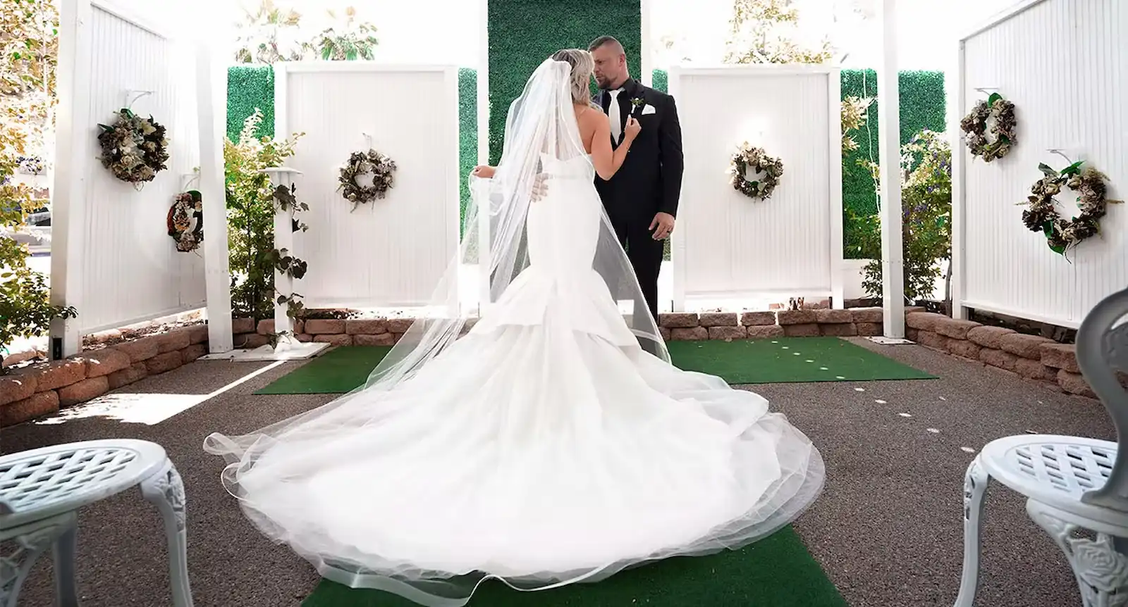 Bride in cathedral veil and groom at the altar during outdoor wedding ceremony in the Bell Garden at Viva Las Vegas