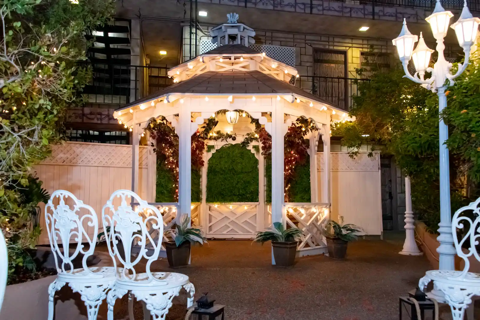 Boulevard Gazebo outdoor wedding venue at night with string lights, white iron chairs, and floral decor at Viva Las Vegas
