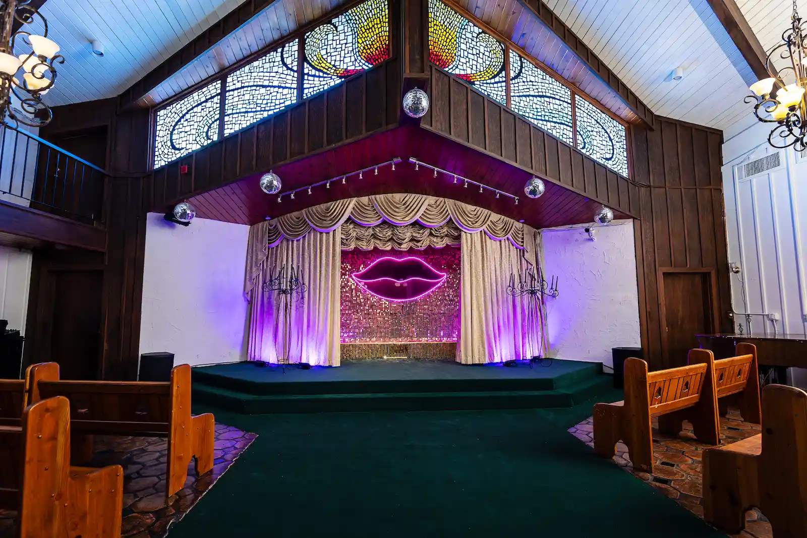 Las Vegas wedding chapel interior with neon lips altar, stained glass windows, disco balls, and wood pews