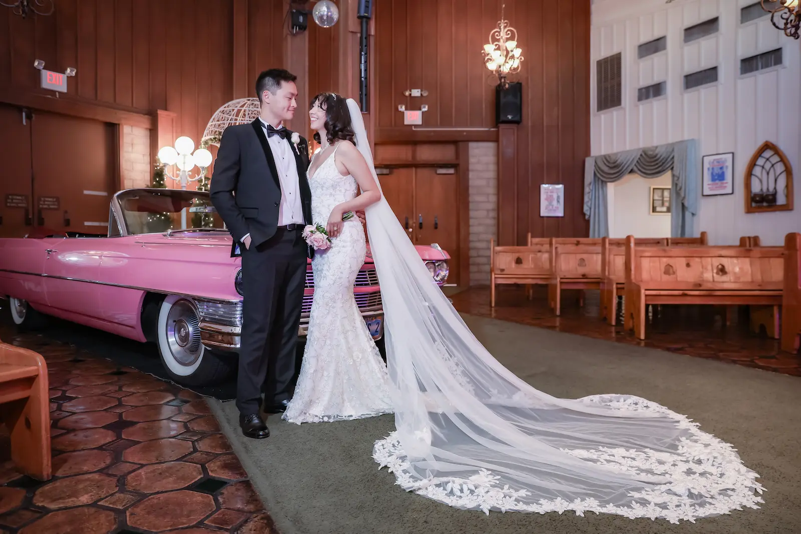 Bride and groom posing with pink Cadillac inside Viva Las Vegas Wedding Chapel