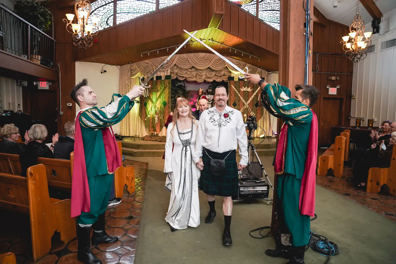 Couple exiting medieval themed wedding ceremony under crossed sword arch at Viva Las Vegas Wedding Chapel