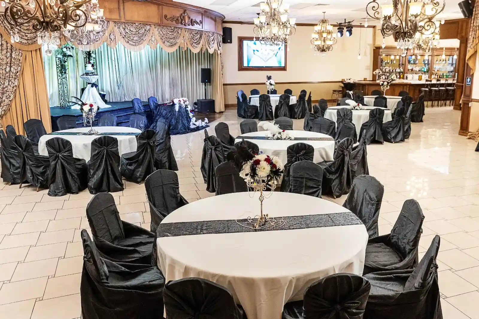Vegas Event Center wedding banquet hall with black chair covers, white linens, crystal chandeliers, and full bar