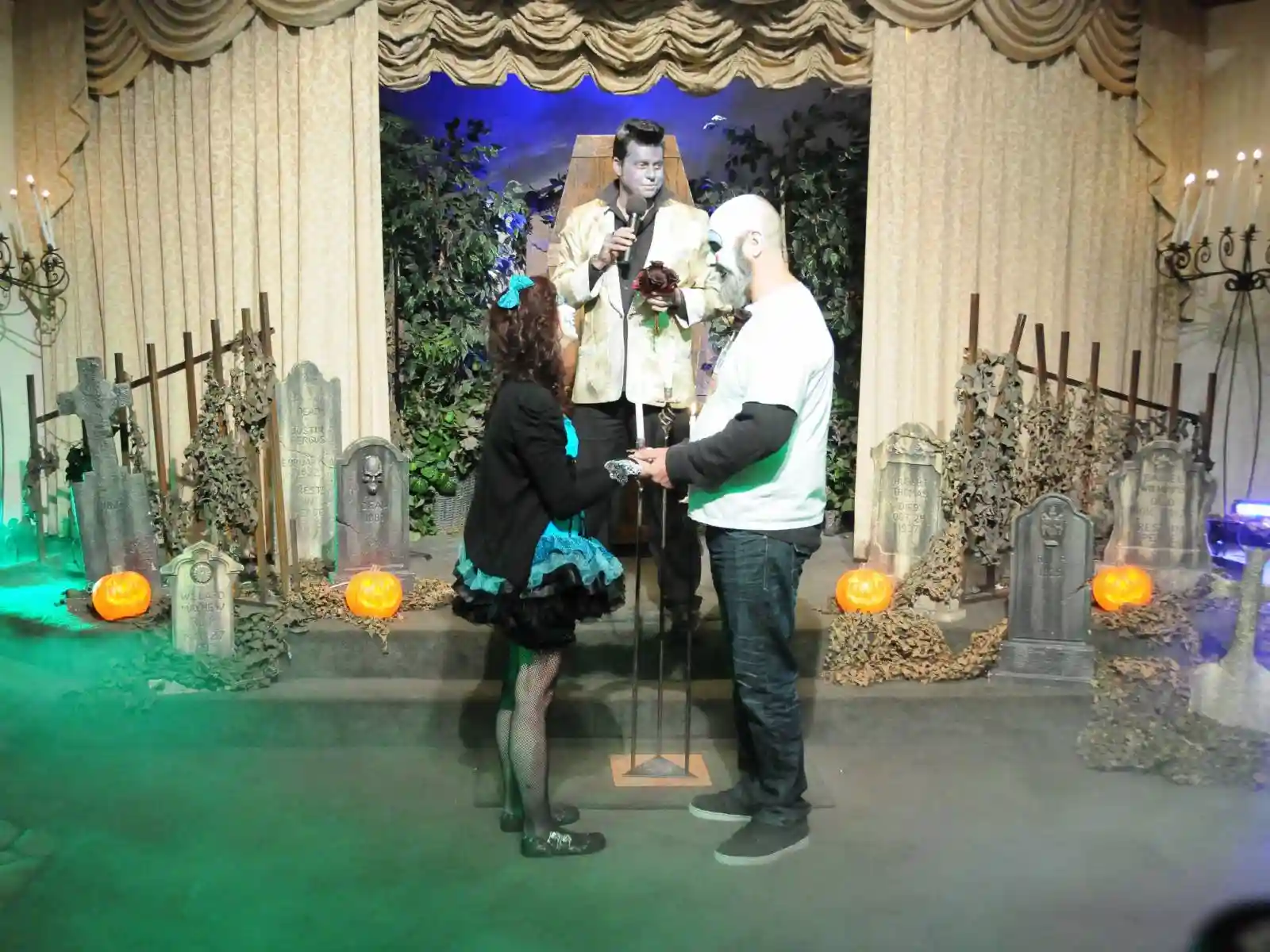 Halloween gothic wedding ceremony at a Las Vegas chapel with graveyard decor, jack-o-lanterns, and Elvis officiant in coffin backdrop